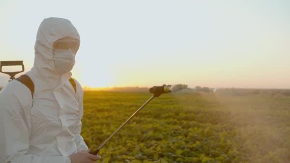 Spray Ecological Pesticide. Farmer Fumigate in Protective Suit and Mask Spraying Fertilizers