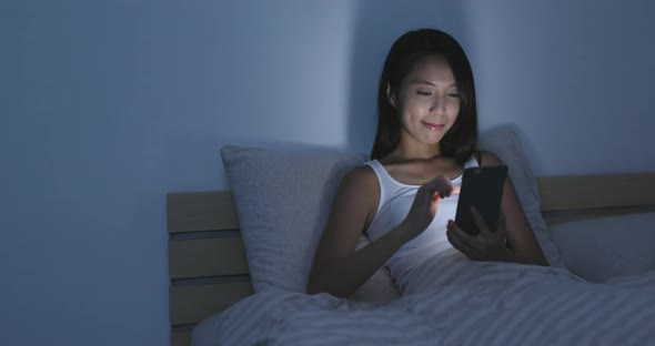 Young Woman using cellphone on bed