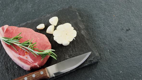 Sirloin chop, knife and garlic on chopping board