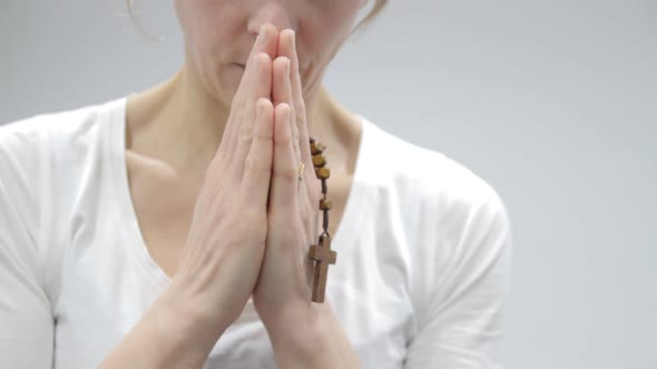 woman praying holding cross in her hands on light background stock video