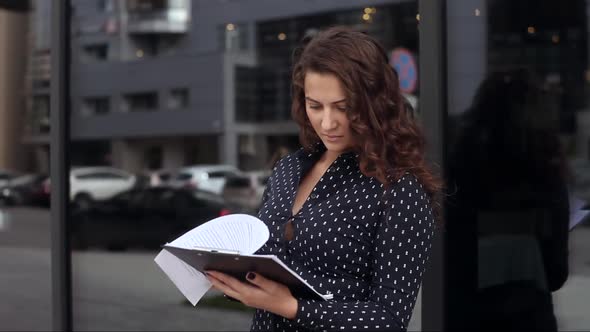 Young Business Woman Looking at Documents Near Office Building
