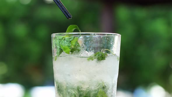 Refreshing summer mojito cocktail in a glass. Woman hand takes a glass of tropical drink mojito