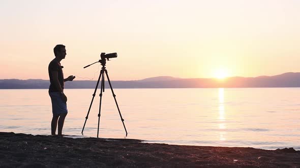 Silhouette Of A Young Man Enjoy Taking Video Of A Sunset In Lake Bracciano, Italy - Wide Shot