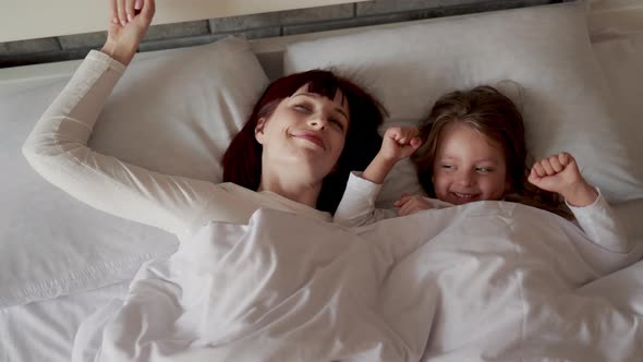 Mother and Daughter Enjoying Time on the Bed While Stretching After After Waking Up