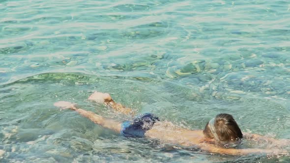 Caucasian boy enjoys swimming at sea of Kalamata, Greece, wearing a sea mask and diving at clear wat