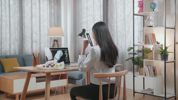 Asian Female Footwear Designer Celebrating Succeed Designing Shoe On A Laptop At Home