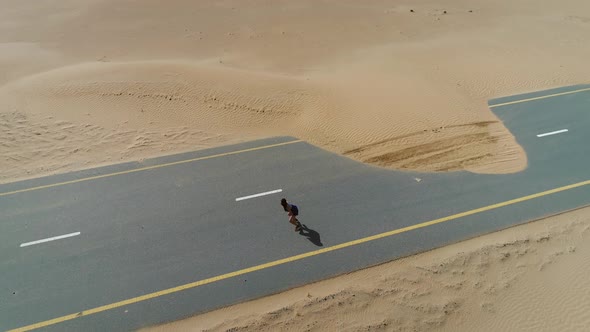 Aerial view of woman doing exercise in road cover by sand on Abu Dhabi, U.A.E