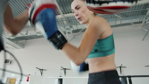 Active Young Sportswoman Exercising with Partner in Gym Practising Boxing Moves