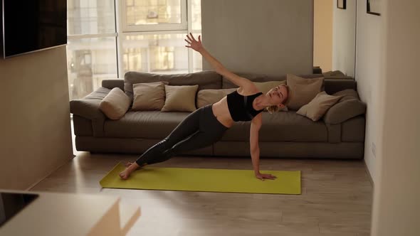 Woman Exercising at Home Practicing Various Yoga Asanas Doing Downward Facing Dog Pose in Living