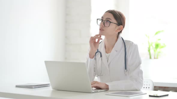 Female Doctor Thinking while Working on Laptop in Office