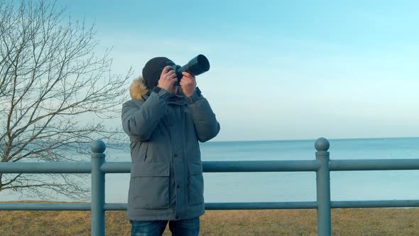 Male Photographer Takes Pictures of the Seascape on a Trip