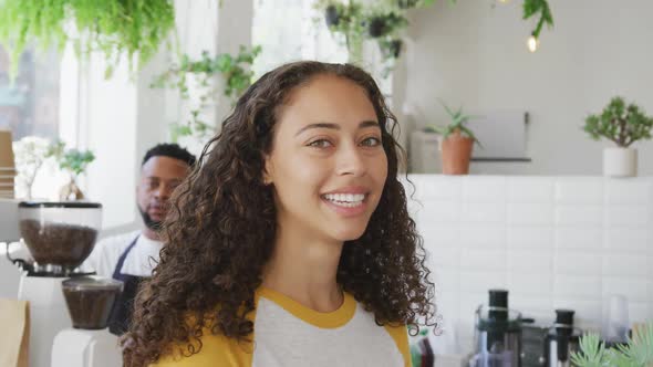 Portrait of happy biracial woman looking at camera and smiling at cafe