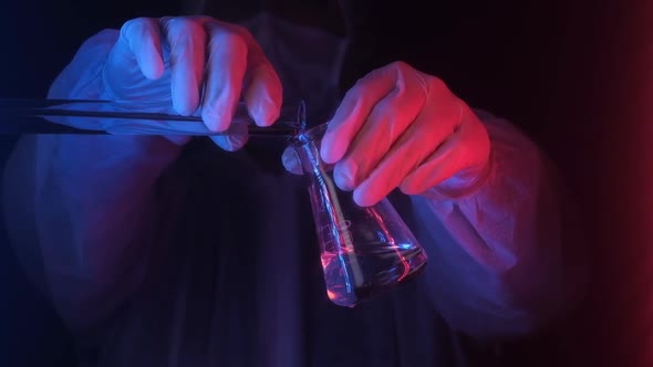 medical scientist in neon light holds test tube with transparent substance