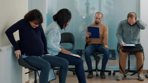 Tired Woman Expecting Child and Waiting in Queue