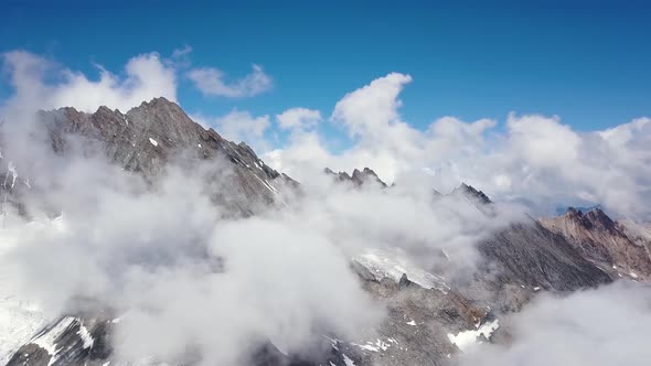 Aerial travelling of sharp edged montain range in the swiss alps with clouds in summer