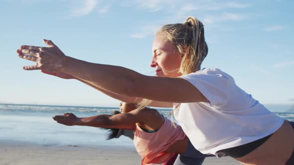 Group of diverse female friends practicing yoga at the beach