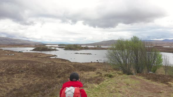 Man adventurer with backpack exploring Highlands in Scotland