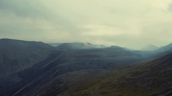 Distant View Of Erupting Volcano With Lava And Smoke On A Cloudy Day. drone shot