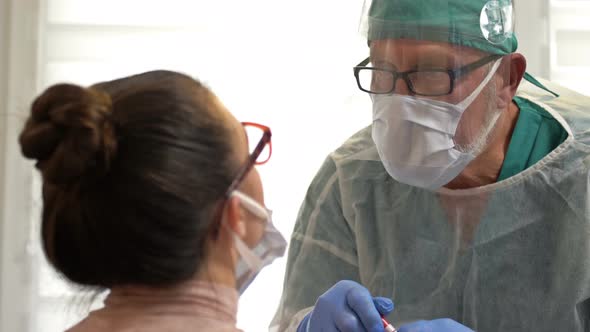 Female Patient Getting Tested with a Buccal Swab for Coronavirus By a Medical Worker Dressed 