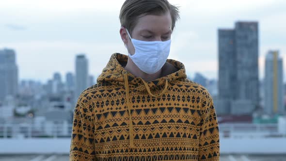 Face of Young Man with Mask Thinking Against View of the City