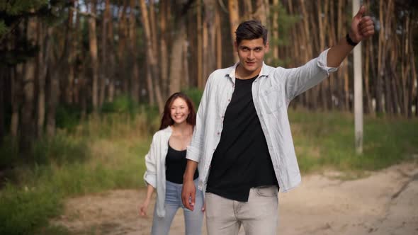 Happy Excited Man and Woman Rejoicing Hitchhiking at Forest Walking to Car Smiling