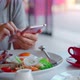 Young woman using smart phone with cup of coffee while eating breakfast. - VideoHive Item for Sale