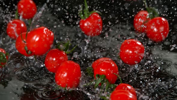 Super Slow Motion Shot of Cherry Tomatoes Flying Into Water on Black Background at 1000Fps