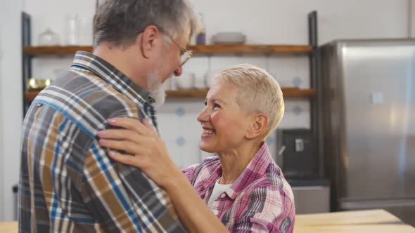 Cheerful Senior Couple in Love Hugging in Kitchen at Home