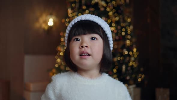 Korean Girl Child in a White Knitted Sweater and Hat Stands