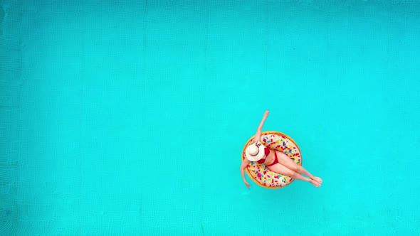 Aerial View of a Woman in Red Bikini Lying on a Donut in the Pool