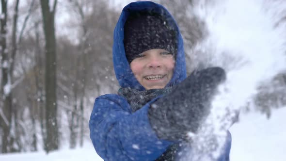 Portrait of a Young Guy Clapping Hand with Snow in the Winter Forest