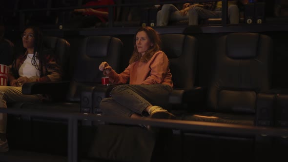 Woman Sitting in Armchair Watching a Movie at the Cinema Alone