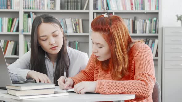 Two Female Students Working on a Project Together at the Library