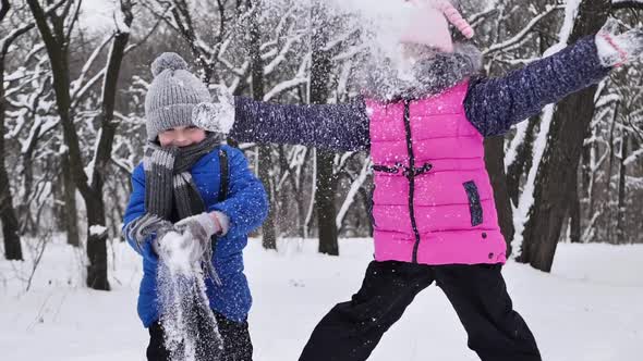 Boy and a Girl are Walking in the Snow in a Winter Forest Throwing Snow on Their Heads