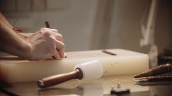 Tailor Makes Holes in a Piece of Leather