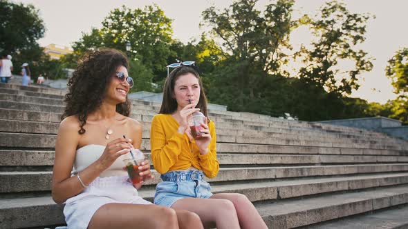 Two Young Models are Drinking Cold Tea Laughing and Talking Enjoying Summer Sunny Day