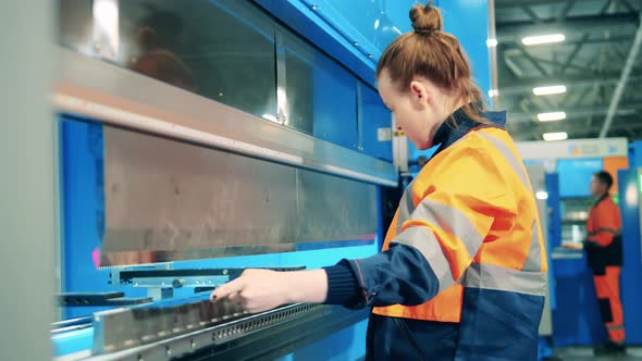 Female Worker Is Using Factory Machine To Bend Metal Piece