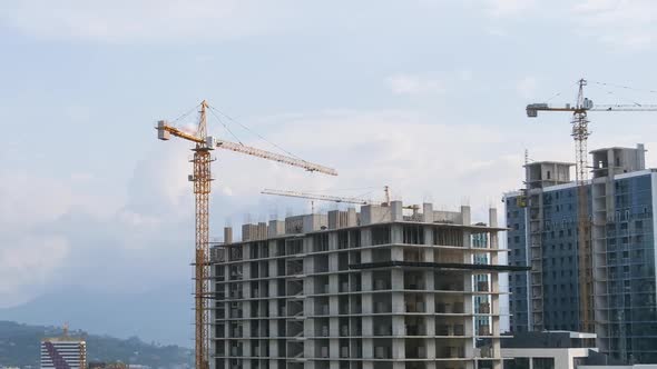 Building Construction. Timelapse. Tower Cranes on a Construction Site Lifts a Load at High-rise