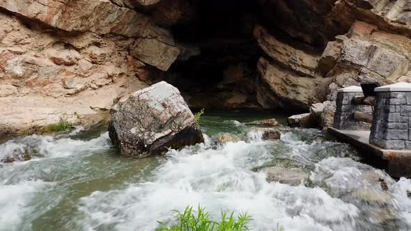 A drone shot of water flowing down from a cavern. (slow motion)