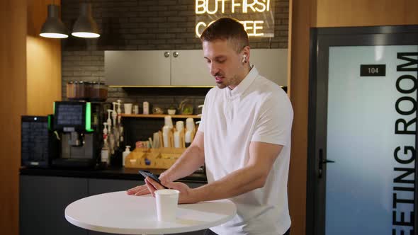 A Young Man During a Video Call on the Phone in an Office Cafe