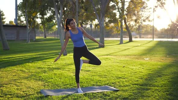 A beautiful young woman yogi laughing while falling over and losing balance in a one legged prayer h