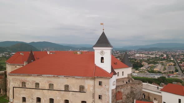 Drone Flies Over Clock Tower in Medieval Castle on Mountain in Small European City at Cloudy Autumn