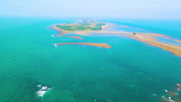 Tropical empty island surrounded by turquoise ocean. Daylight aerial overview