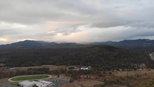 Aerial view of storm clouds over the mountains outside of a small town school track field