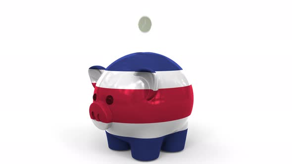 Coins Fall Into Piggy Bank Painted with Flag of Costa Rica alt