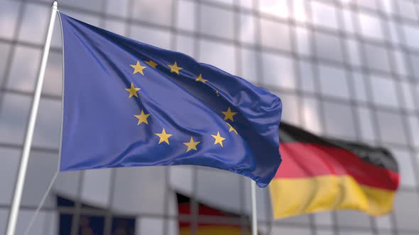 Waving Flags of the EU and Germany in Front of a Modern Skyscraper