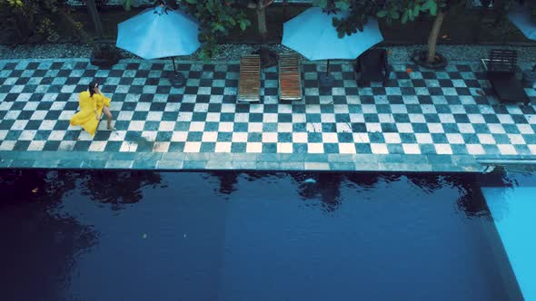 Asian Woman in Yellow Run Along the Pool