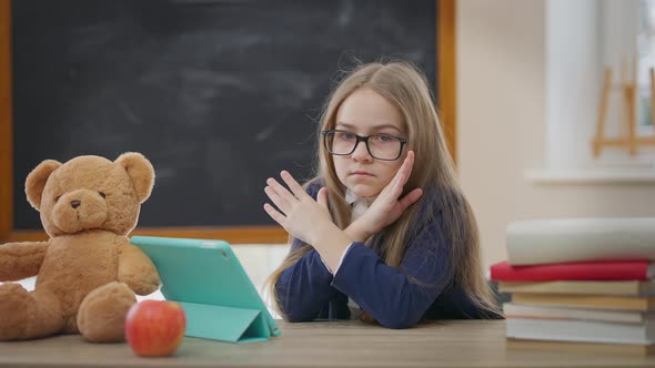 Exhausted Caucasian Girl Gesturing No Crossing Hands Looking at Camera Sitting in School Classroom
