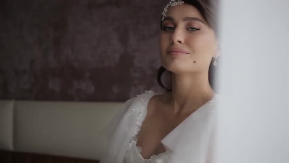 Beautiful Millennial Bride with a Wreath on Her Head and in a White Wedding Dress Holds a Bouquet of