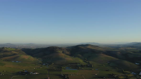Aerial of hills, vineyard farmlands landscape and ponds, Stellenbosch, pan down